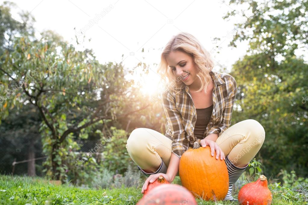 young woman in garden harvesting pumpkins