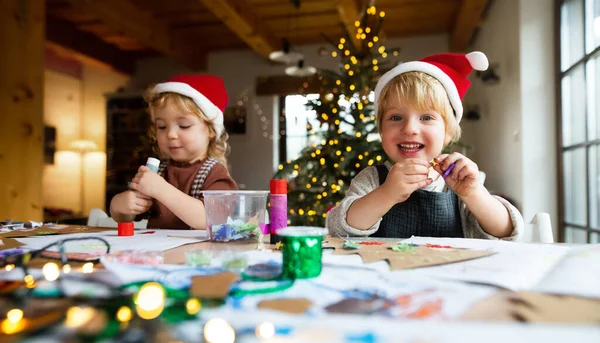 Portré kislányról és fiúról otthon karácsonykor, művészettel és kézműves munkával. — Stock Fotó