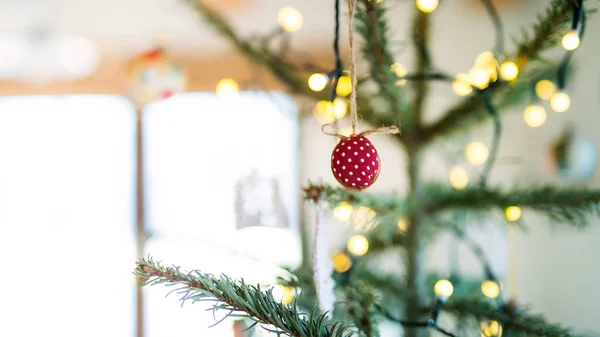 Ornement rouge de bricolage accroché à la branche d'arbre de Noël à l'intérieur à la maison. — Photo