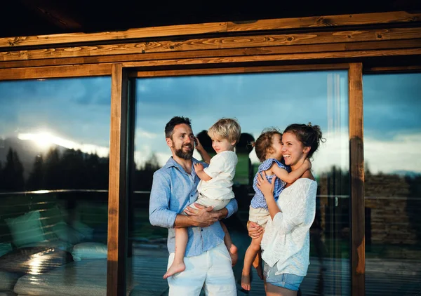 Οικογένεια με μικρά παιδιά που στέκονται δίπλα σε ξύλινη καμπίνα, διακοπές στη φύση έννοια. — Φωτογραφία Αρχείου