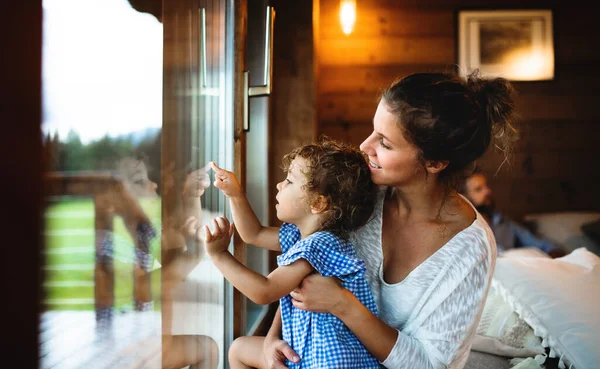 Piccola ragazza con genitori in cabina di legno, concetto di vacanza nella natura. — Foto Stock