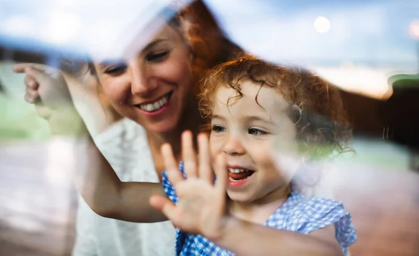 Ragazza piccola con madre da finestra, vacanza nel concetto di natura. Girato attraverso il vetro. — Foto Stock