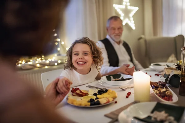 Menina pequena com avós sentados dentro de casa celebrando o Natal juntos. — Fotografia de Stock