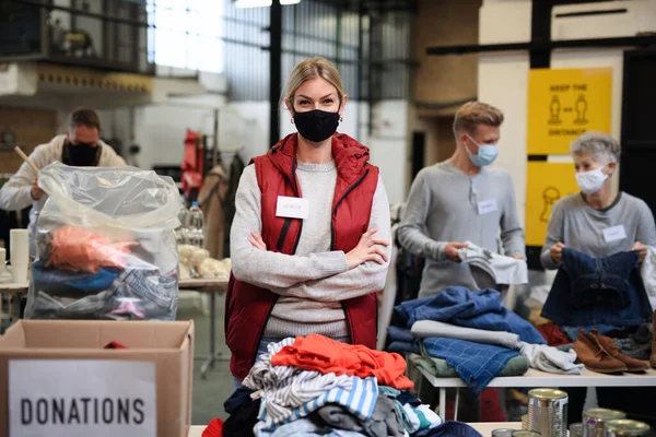 Добровольцы, работающие с продуктами питания и одеждой в общественном благотворительном центре, концепция коронавируса. — стоковое фото