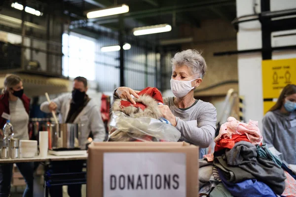 Bénévoles travaillant avec de la nourriture et des vêtements dans le centre de dons de charité communautaire, concept de coronavirus. — Photo