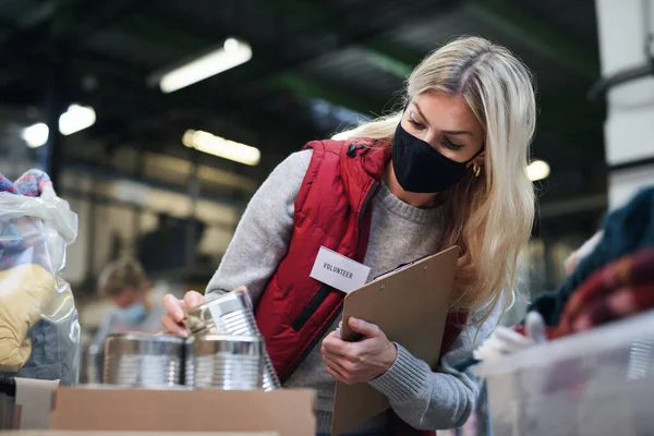 Woman volunteer in community charity donation center, food bank and coronavirus concept. — Stock Photo, Image