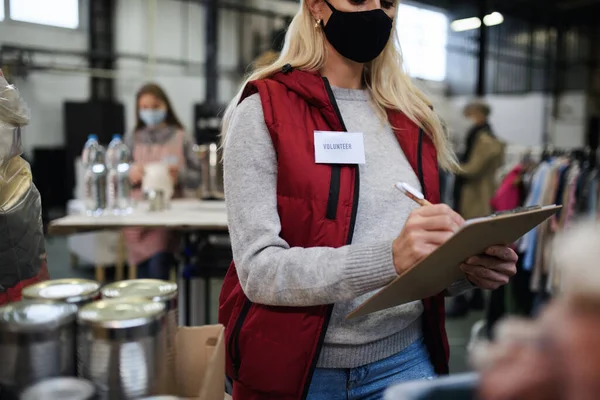 Volontärer som arbetar med mat och kläder i välgörenhetscentrum, coronavirus koncept. — Stockfoto