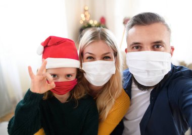 Noel 'de evde küçük kızları olan bir aile yüz maskeleriyle selfie çekiyor..