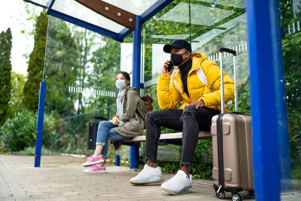 Jóvenes con smartphone en parada de autobús al aire libre en la ciudad. Concepto de Coronavirus. — Foto de Stock