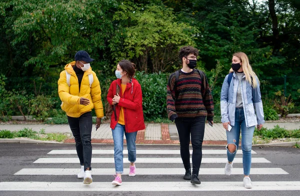 Gruppo di giovani che attraversano la strada all'aperto in città, parlando. Concetto di coronavirus. — Foto Stock