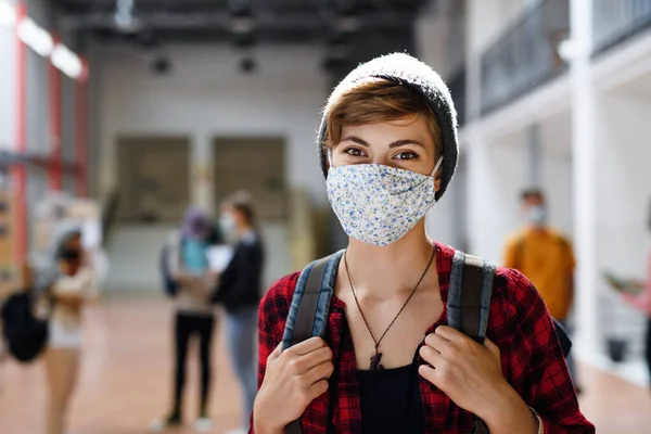 Νεαρός φοιτητής με μάσκα προσώπου πίσω στο κολέγιο ή το πανεπιστήμιο, έννοια coronavirus. — Φωτογραφία Αρχείου