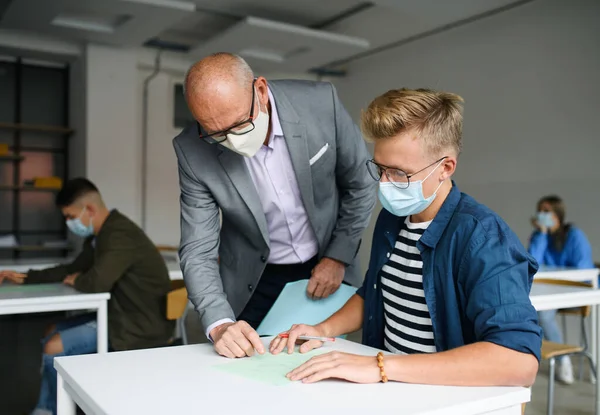 Young students with teacher at desks at college or university, coronavirus concept. — Stock Photo, Image