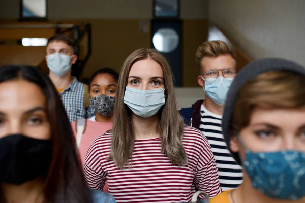 Вид спереди на молодых студентов в масках для лица в колледже или университете, концепция коронавируса. — стоковое фото