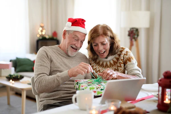 Старша пара, яка відчиняє двері вдома на Різдво, має відеодзвінок з родиною.. — стокове фото