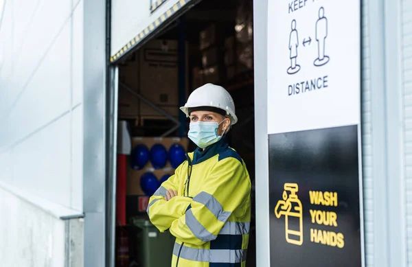 Женщина в маске, стоящая перед складом, коронавирусная концепция. — стоковое фото