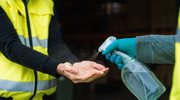 Unrecognizable warehouse workers disinfecting hands, coronavirus concept.