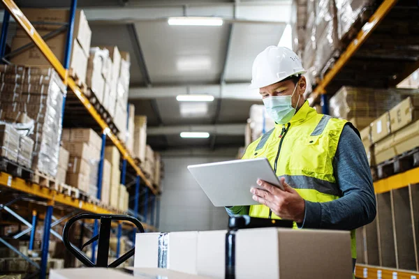 Mann arbeitet mit Tablette in Lagerhalle, Coronavirus-Konzept. — Stockfoto