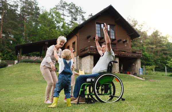 Petits enfants avec grands-parents aînés en fauteuil roulant. — Photo