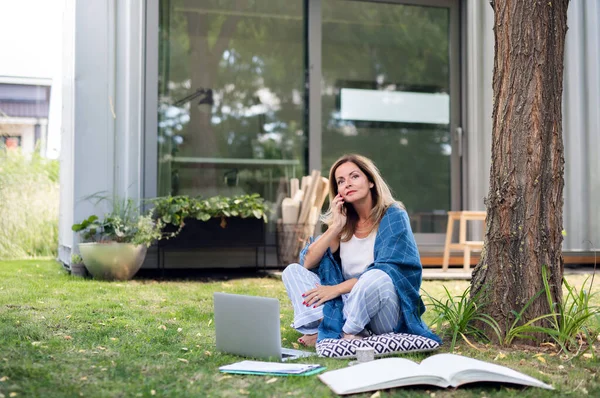 Mujer madura en pijama trabajando en casa oficina al aire libre en el jardín, usando teléfono inteligente. —  Fotos de Stock
