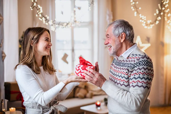 Homem sênior dando presente à neta feliz em casa no Natal. — Fotografia de Stock