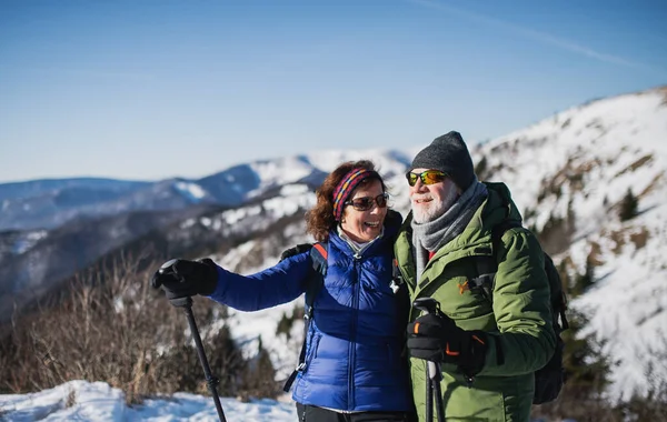 在冰雪覆盖的冬季，有北方步行杆的老夫妇徒步旅行者. — 图库照片