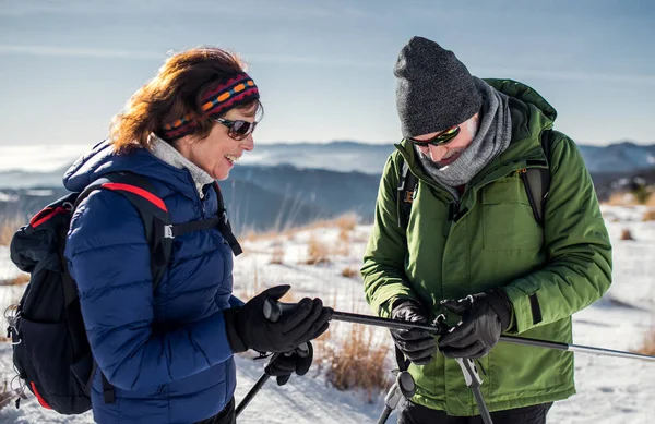 Senior par vandrare med nordiska promenadstavar i snötäckt vinternatur. — Stockfoto