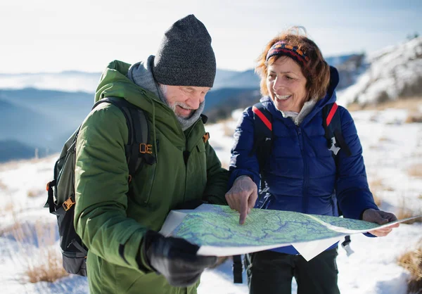 Karla kaplı kış doğasında harita kullanan yaşlı çiftler.. — Stok fotoğraf
