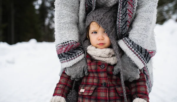 Mãe irreconhecível com pequena filha de pé na natureza de inverno. — Fotografia de Stock