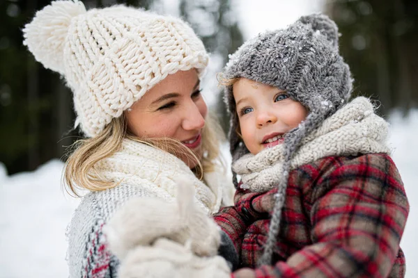 Alegre madre con pequeña hija de pie en la naturaleza de invierno, riendo. —  Fotos de Stock