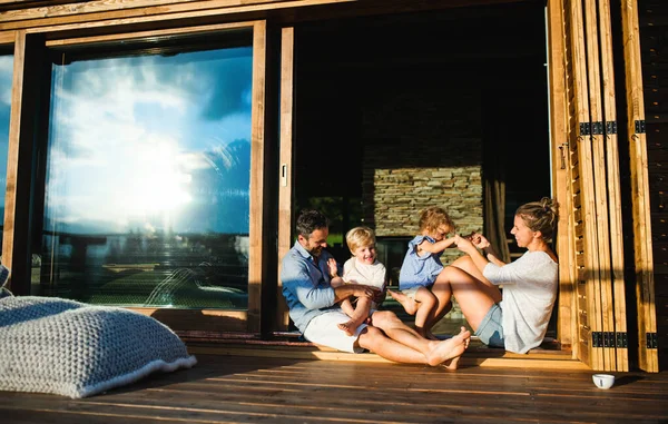 小さな子供たちが木造キャビンのパティオに座っている家族、自然のコンセプトで休日. — ストック写真