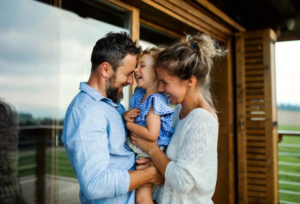Famiglia con piccola figlia in piedi sul patio della cabina in legno, concetto di vacanza nella natura. — Foto Stock