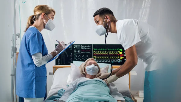 Ärzte und Covid-19 infizierter Patient im Krankenhausbett, Coronavirus-Konzept. — Stockfoto