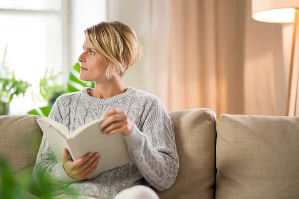 Porträtt av kvinna avkopplande med bok inomhus, mental hälsovård koncept. — Stockfoto