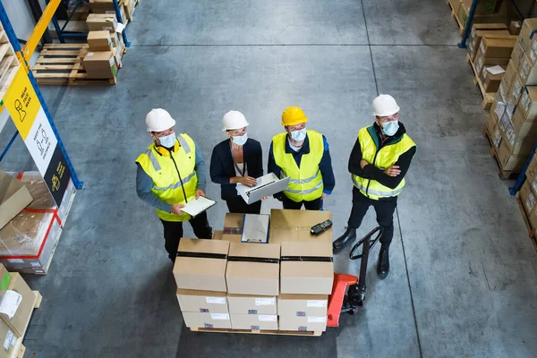 Draufsicht auf eine Gruppe von Arbeitern mit einem Manager, der im Lager arbeitet, Coronavirus-Konzept. — Stockfoto