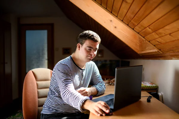 唐氏综合征成年男子坐在家中卧房里，用笔记本电脑. — 图库照片