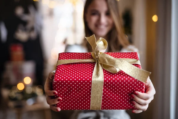 Feliz joven mujer en casa en Navidad, sosteniendo presente. — Foto de Stock