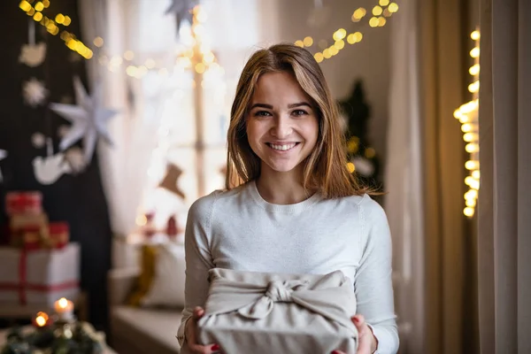 Joyeux jeune femme à l'intérieur à la maison à Noël, tenant présent. — Photo