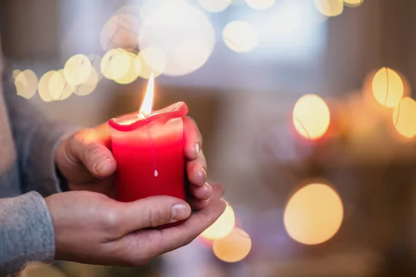 Närbild av händerna på mogen man inomhus vid jul, håller ljus. — Stockfoto