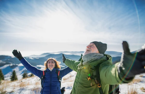 Senioři pár turisté ve sněhem pokryté zimní přírodě, protáhnout paže. — Stock fotografie