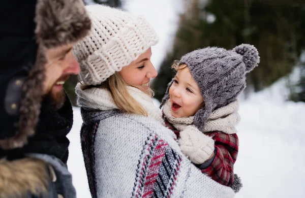 Vader en moeder met klein kind in de winternatuur, staand in de sneeuw. — Stockfoto