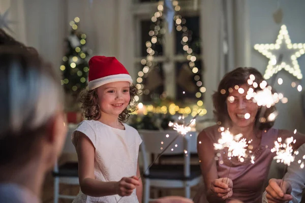 Kleines Mädchen mit Eltern und Großeltern mit Wunderkerzen im Haus feiern Weihnachten. — Stockfoto