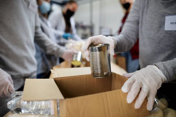 Midsection of group of volunteers in community donation center, food bank and coronavirus concept. — Stock Photo, Image