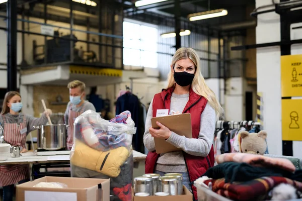 Voluntário trabalhando com alimentos e roupas no centro comunitário de doações de caridade, conceito de coronavírus. — Fotografia de Stock