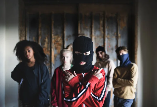 Niño con máscara con adolescentes pandilla interior en edificio abandonado, mostrando gesto de arma de dedo. — Foto de Stock