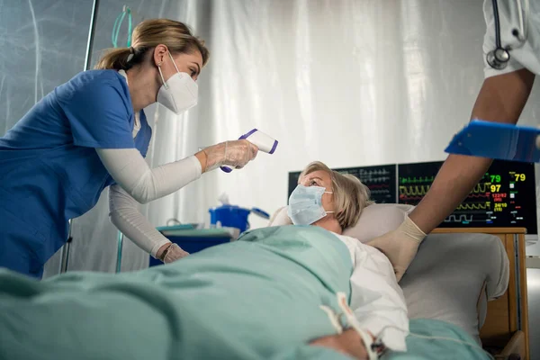 Médecin et patient infecté par le covide-19 au lit à l'hôpital, coronavirus et concept de mesure de la température. — Photo