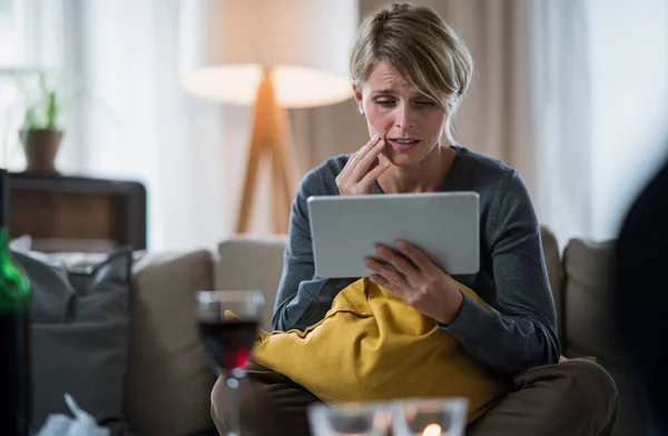 Vrouw met tablet binnen op de bank thuis gevoel van stress, geestelijke gezondheid concept. — Stockfoto