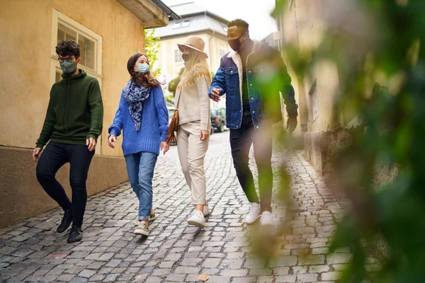 Grupo de jovens com máscara facial ao ar livre na cidade, andando. Conceito de coronavírus. — Fotografia de Stock