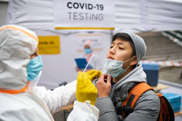 Jovem em covid-19 centro de testes ao ar livre na rua, coronavírus e tomando conceito de swab. — Fotografia de Stock