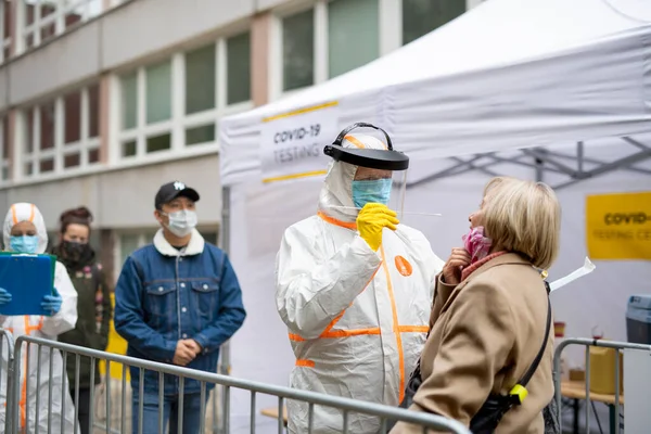 Az emberek várnak covid-19 vizsgálati központ szabadban az utcán, coronavirus koncepció. — Stock Fotó