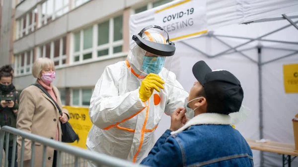 Молодий чоловік у центрі тестування на вулиці на вулиці, коронавірус та концепція прийому тампона . — стокове фото